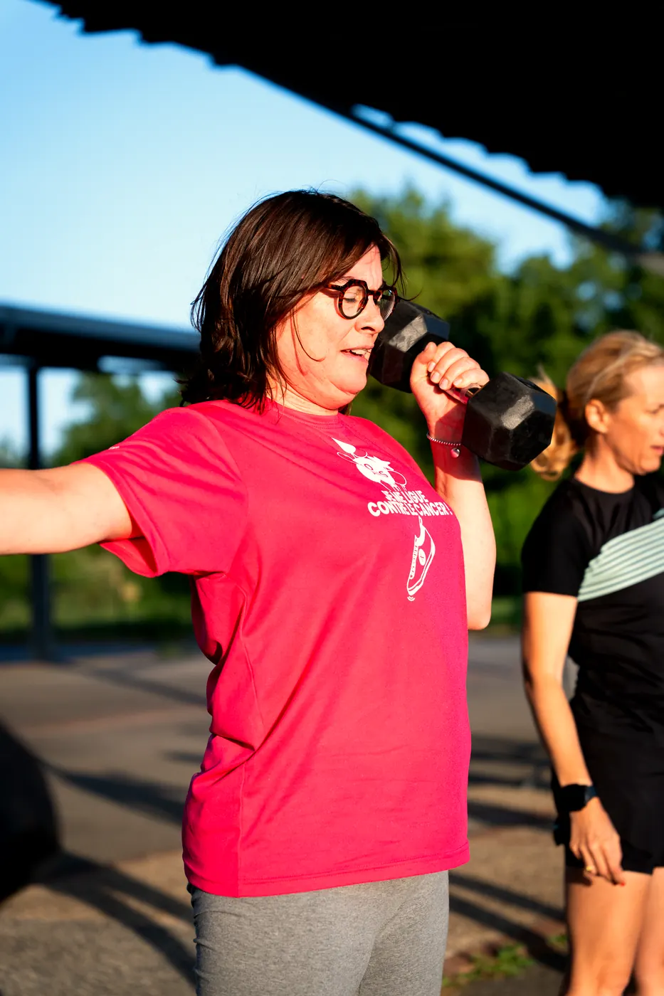 Une participante souriante en t-shirt rose avec un kettlebell
